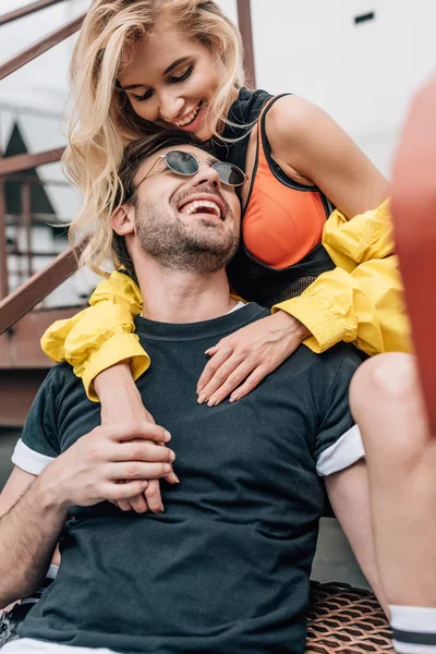 屋根の上で抱きしめて微笑むメガネのブロンドの女性とハンサムな男 — ストック写真