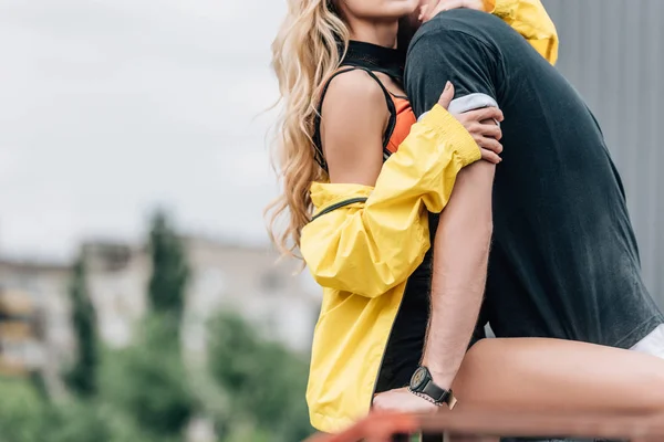 cropped view of woman in yellow jacket hugging with man in t-shirt