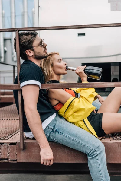 Sarışın Kadın Içme Şampanya Adam Çatıda Oturan Yan Görünümü — Stok fotoğraf