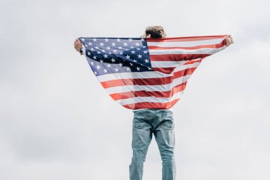 çatı üzerinde Amerikan bayrağı tutan kot adam arka görünümü 