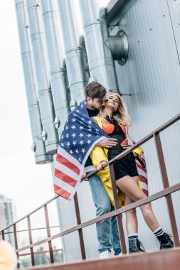 çatı üzerinde sarılmak Amerikan bayrağı ile çekici kadın ve yakışıklı adam 