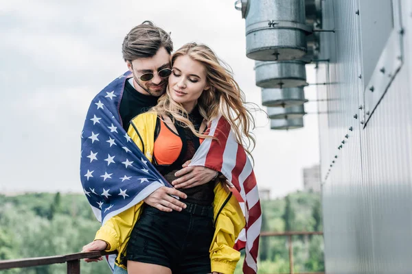çatı üzerinde sarılmak Amerikan bayrağı ile çekici kadın ve yakışıklı adam 