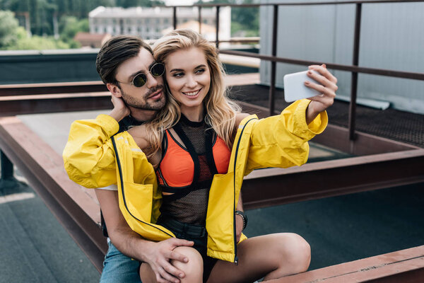 beautiful woman in yellow jacket taking selfie with handsome man 