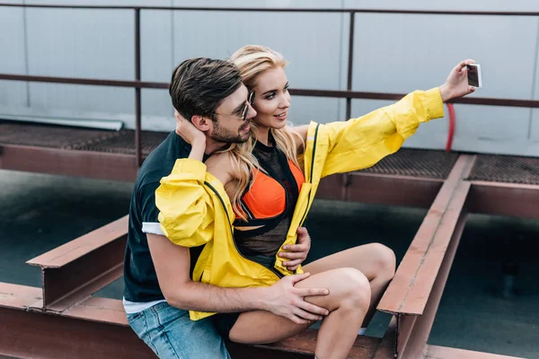 ハンサムな男と自分撮りを取る黄色のジャケットの美しい女性 — ストック写真