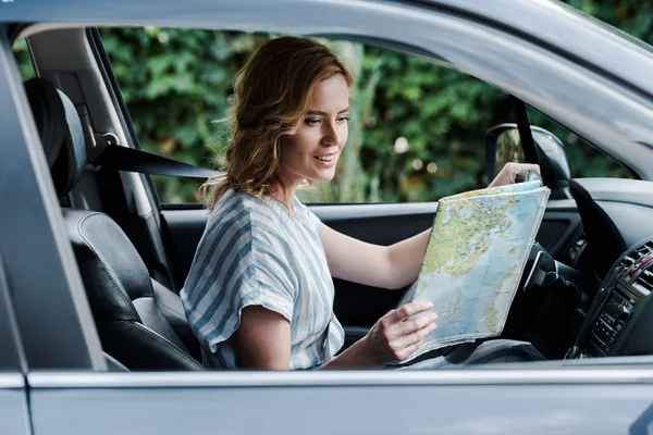 지도를보고 자동차를 운전하는 매력적인 여성의 선택적 — 스톡 사진