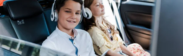 Panoramiczny Strzał Chłopca Słuchania Muzyki Słuchawkach Pobliżu Siostry Samochodzie — Zdjęcie stockowe