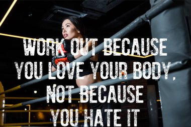 low angle view of attractive woman in boxing gloves standing in sports center with work out because you love your body, not because you hate it illustration clipart