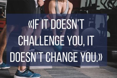 Spor salonunun yanında duran spor hocasının kesikli görüntüsü motivasyon yazısıyla birlikte dambılı kaldırıyor.