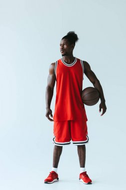 gri arka planda topu tutarak uzak görünümlü yakışıklı Afrikalı Amerikan basketbol oyuncusu