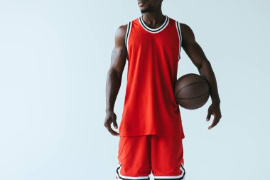 Afrika Amerikan basketbol oyuncusu gri üzerinde izole topu tutan kırpılmış görünümü