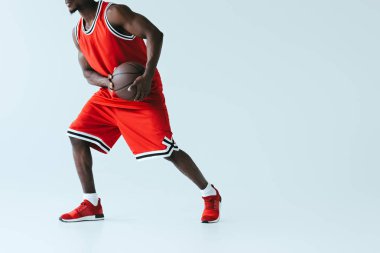 gri arka planda basketbol oynarken kırmızı spor sporu Afrikalı Amerikan sporcu kısmi görünümü