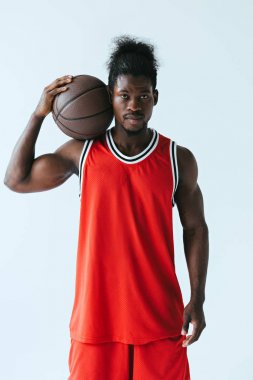 basketbol topu ile ciddi Afrikalı Amerikan sporcu gri üzerinde izole kamera bakıyor