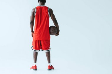 Afrika Amerikan sporcu gri arka planda tutan basketbol topu arka görünümü