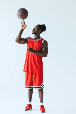 yakışıklı Afrikalı Amerikan basketbol oyuncusu gri arka planda topu ile oynuyor