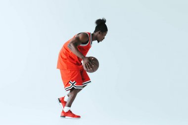 atletik Afrikalı Amerikan sporcu gri arka planda basketbol oynuyor