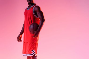 degrade ile pembe arka planda Afrika Amerikan basketbol oyuncusu tutarak topu kırpılmış görünümü