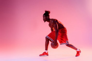shirtless, muscular african american sportsman playing basketball on pink and purple gradient background with lighting  clipart