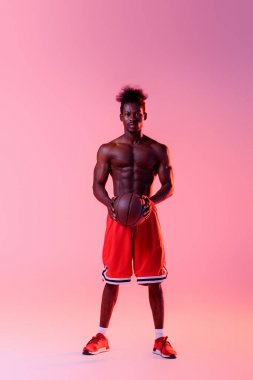 ışık ile pembe ve mor degrade arka planda kamera bakıyor kas gövdesi ile emin Afrikalı Amerikan basketbol oyuncusu 