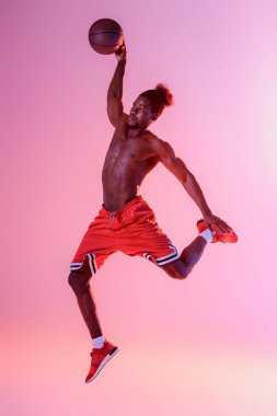 kaslı gövde ile Afrikalı Amerikan sporcu pembe ve mor degrade arka planda basketbol oynuyor