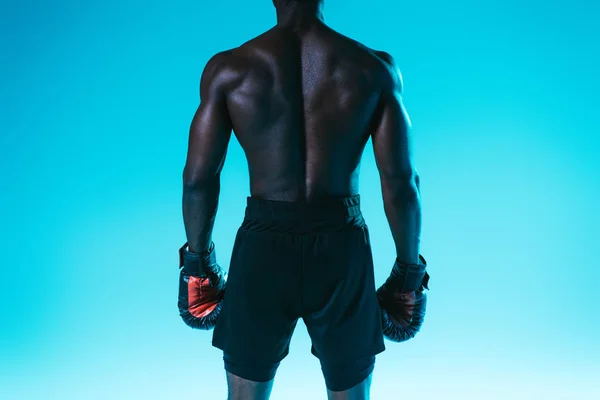 肌肉发达的非洲美国运动员短裤和拳击手套在蓝色背景的背面视图 — 图库照片