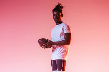degrade ile pembe arka plan üzerinde emin African American sporcu tutan Rugby topu 