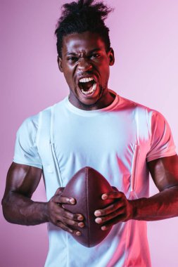 degrade ile mor arka planda Rugby topu tutarken heyecanlı African American sporcu kamera çığlık