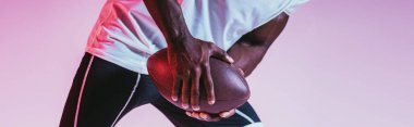 degrade ile mor arka planda Amerikan futbolu oynayan Afrikalı Amerikan sporcu kırpılmış görünümü, panoramik çekim