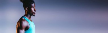 aydınlatma ile gri ve mavi degrade arka planda uzak görünümlü genç Afrikalı Amerikan sporcu panoramik çekim