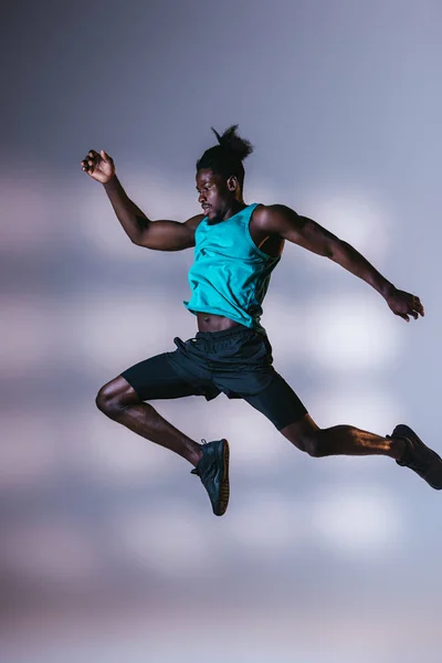 Ung Atletisk Afrikansk Amerikansk Sportsman Hoppa Grå Bakgrund Med Belysning — Stockfoto