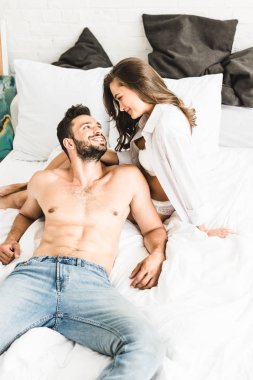 seksi mna yatakta yatarken kız adam yanında oturan ve birbirlerine bakarak