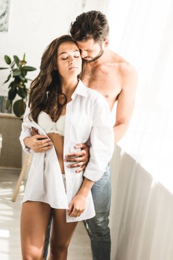 pencere ve kapalı gözleri ile sarılma yakın seksi genç çift ayakta