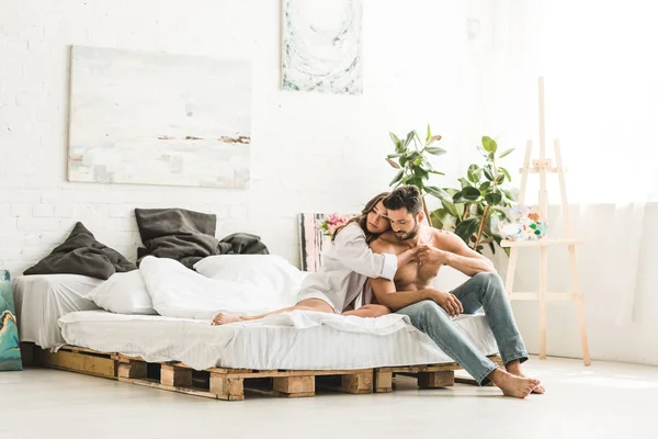 年轻夫妇拥抱 而坐在床上 看着远方 — 图库照片