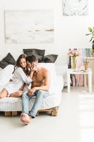 年轻的夫妇在爱坐在床上 拥抱与闭着眼睛 — 图库照片