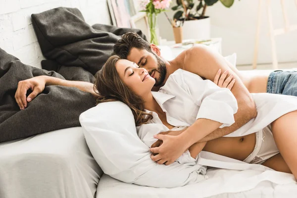 seksi genç çift uyuyan ve yatakta sarılmak