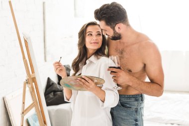 Genç sanatçı çizim iken erkek arkadaş tutan cam şarap ve sarılma kız arka