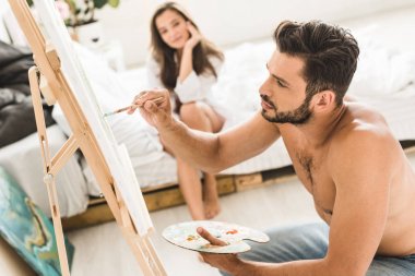 seksi gömleksiz adam çizim ve kız yatakta oturan seçici odak