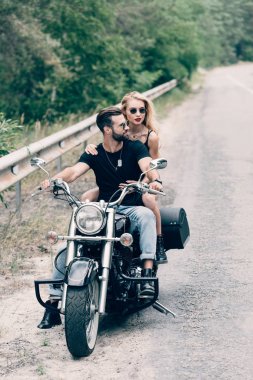 yeşil orman yakınındaki yolda siyah motosiklet üzerinde bisikletçileri genç çift