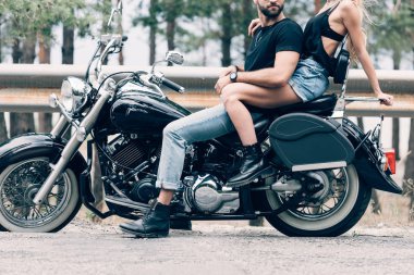 yolda siyah motosiklet üzerinde bisikletçilerin genç çift kırpılmış görünümü