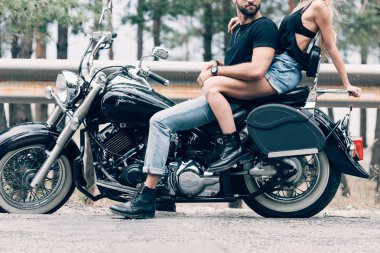 cropped view of young couple of bikers on black motorcycle on road clipart