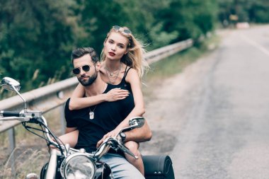 yeşil orman yakınındaki yolda siyah motosiklet kucaklayan bisikletçilerin genç çift