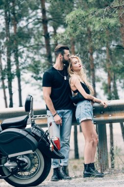 bisikletçilerin genç çift yeşil orman yakınındaki yolda siyah motosiklet yakınında kucaklayan