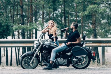 siyah motosiklet ve adam yeşil orman yakınındaki yolda şişealkol içme oturan bisikletçileri genç çift