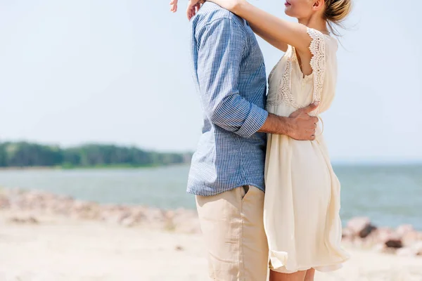 ビーチで抱きしめるロマンチックなカップルのトリミングされたビュー — ストック写真