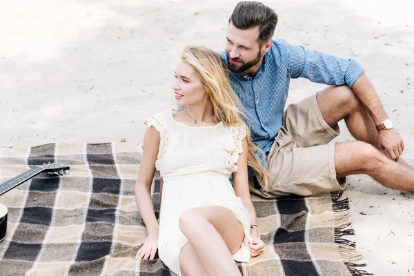 Beautiful Young Couple Sitting Plaid Blanket Looking Away Sandy Beach — Stock Photo, Image