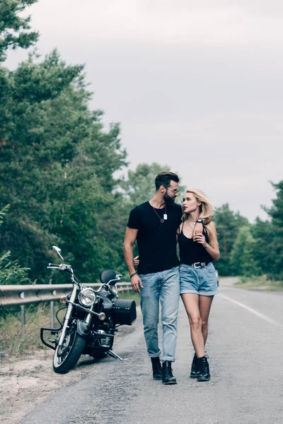 Joven Pareja Ciclistas Caminando Por Carretera Abrazando Cerca Motocicleta Negro —  Fotos de Stock