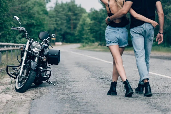 Cropped View Young Couple Bikers Walking Road Embracing Black Motorcycle — Stock Photo, Image