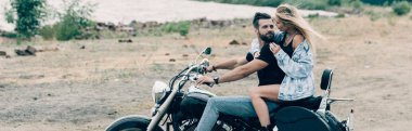 nehir yakınındaki kumlu plajda siyah motosiklet üzerinde sarılma bisikletçileri genç çift, panoramik çekim