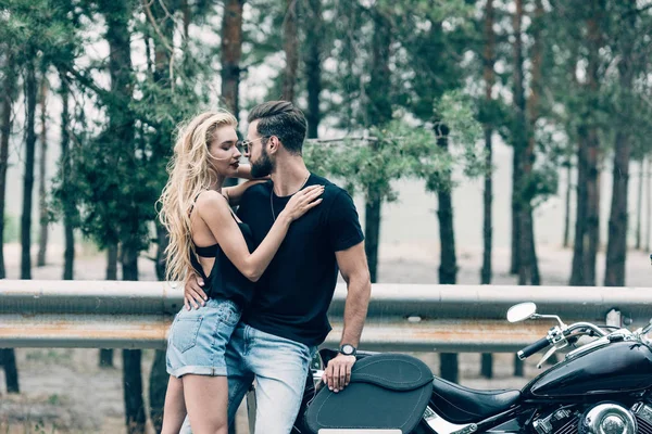 Joven Pareja Ciclistas Tiernamente Abrazando Cerca Negro Motocicleta Carretera Cerca —  Fotos de Stock