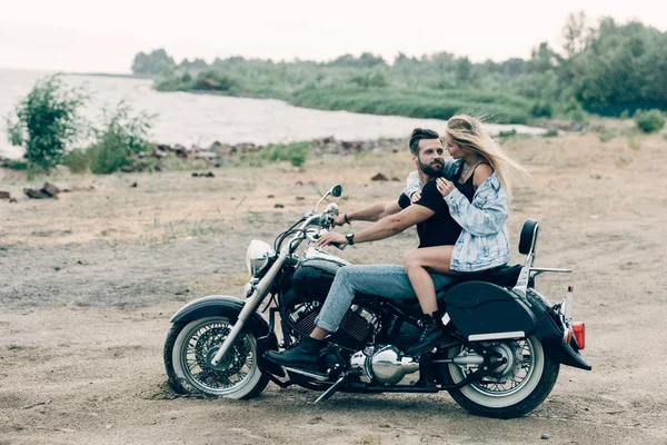 Young Couple Bikers Hugging Black Motorcycle Sandy Beach River — Stock Photo, Image