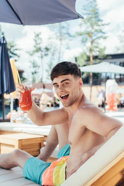 Jovem Alegre Sorrindo Para Câmera Enquanto Sentado Salão Chaise Com — Fotografia de Stock